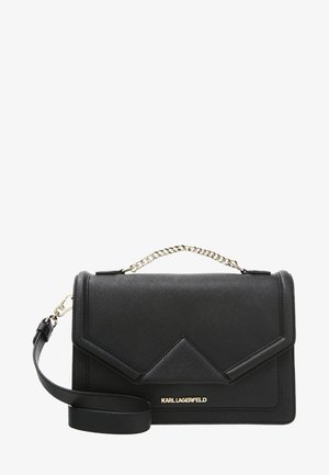 Schwarze Karl Lagerfeld Lederhandtasche mit goldenem Logo, Ketten-Obergriff und angebrachtem verstellbaren Schulterriemen auf weißem Hintergrund.
