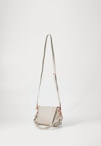 Beige bőr keresztpántos táska megkötött pánttal és rózsaarany fémalkatrészekkel. Simább textúra és kompakt téglalap alak. Cipzáras zárás.