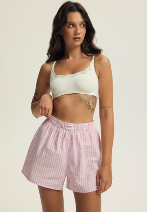 Jasnoróżowe i białe szorty w kratkę z elastycznym pasem i metką. Połączone z białym stanikiem typu bralette z koronkowymi detalami.
