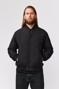 Veste bomber matelassée noire avec col rond, boutons-pression et poignets côtelés. Présente une texture douce et des accents de design minimalistes.