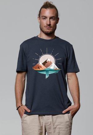 Navyblauwe t-shirt met een afbeelding van bergen en een zon in aardetinten, met een gladde textuur en korte mouwen.