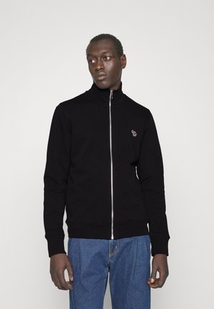 Black zip-up sweatshirt in cotton blend, featuring a high collar, ribbed cuffs, and a small embroidered logo on the chest. Paired with blue jeans.