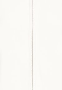 Gros plan sur un tissu blanc montrant une fermeture éclair métallique argentée courant verticalement au centre avec des coutures visibles sur les côtés.