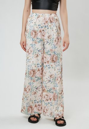 Floral wide-leg pants made of lightweight fabric; pastel pink with rose and blue floral patterns; elastic waistband; paired with black sandals.