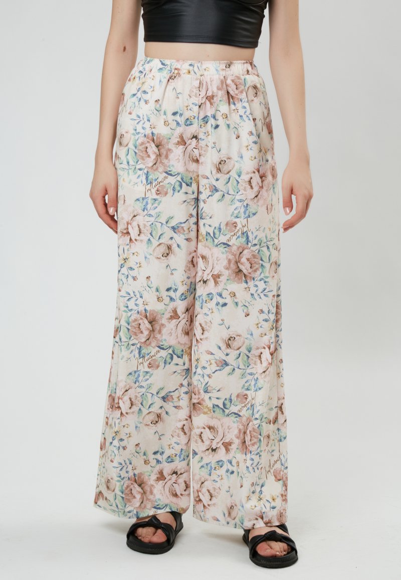 Floral wide-leg pants made of lightweight fabric; pastel pink with rose and blue floral patterns; elastic waistband; paired with black sandals.