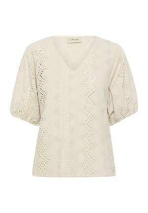 Bijela bluzica s V-izrezom, kratkim napufanim rukavima, teksturiranom tkaninom koja sadrži geometrijske izreze i cik-cak uzorke na prednjem dijelu.