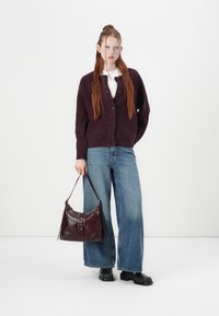 Burgundy knit cardigan with button closure, paired with wide blue jeans and a dark red leather bag featuring a buckle detail. Black ankle boots.