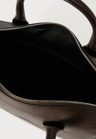 Bolso de cuero marrón con cierre de cremallera, que presenta un interior negro espacioso, asas resistentes y una superficie exterior texturizada.