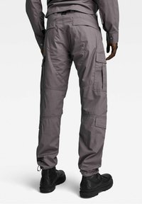 Šedé cargo kalhoty s mnoha kapsami, nastavitelnými manžetami a mírně zúženým střihem. Vyrobené z lehkého a odolného materiálu.