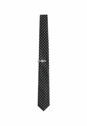 Black silk tie with a repeated small white floral pattern, featuring a silver tie clip for secure fastening. Tapered end, smooth texture.