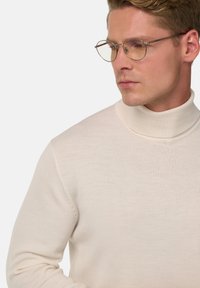 Kremkrāsas augsta apkakle džemperis, kas izgatavots no mīksta auduma, ar pieguļošu dizainu un ribotām apkaklēm. Caurspīdīgas apļa brilles papildina izskatu.