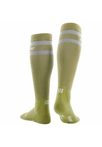 Groene kniekousen met compressie tot net onder de knie, voorzien van ribbeltextuur en zilveren strepen. Ze hebben gepolsterde delen en stippen met grip op de zolen.