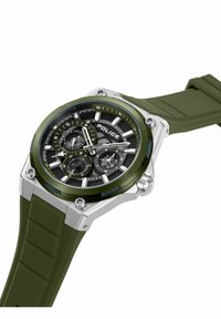Reloj con correa de silicona verde que presenta un dial negro redondo con manecillas plateadas, múltiples subdiales y una caja de acero inoxidable de tono plateado.