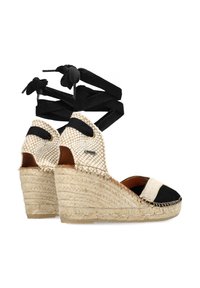 Sandali con zeppa dalla base in paglia naturale intrecciata, con cinturini neri e una tomaia in tessuto a quadri crema con accenti neri.