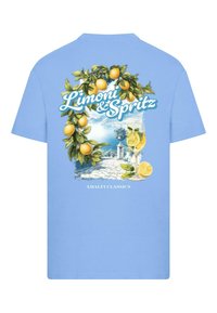Šviesiai mėlynas medvilninis marškinėliai su grafiniu graviravimu, vaizduojančiu citrinas, pakrantės peizažą ir tekstu "Limoni & Spritz Amalfi Classics".
