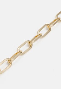 Chaîne en métal doré avec des maillons rectangulaires allongés. Surface polie, texture lisse et espacement régulier entre les maillons. Aucun accent supplémentaire.