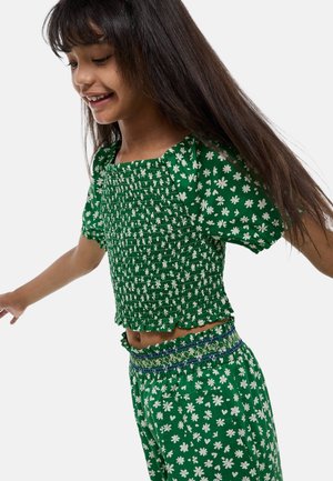 Haut smocké à motifs floraux verts avec de courtes manches bouffantes, associé à un pantalon assorti avec taille élastique et bord décoratif.