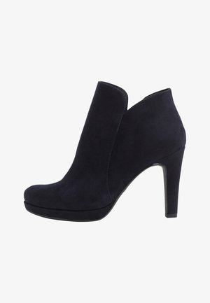 Černá semišová kotníková bota na vysokém podpatku s oblou hranou vrchní části a zaoblenou špičkou, zobrazena z vnější strany na bílém pozadí.