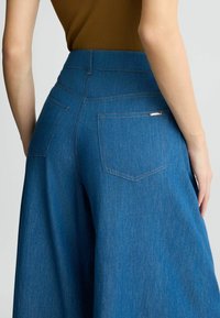 Jeans-Culottes in Mittelblau mit hoher Taille. Verfügt über dezente Nähte, zwei Gesäßtaschen und ein metallicfarbenes Markenlabel an einer Tasche.