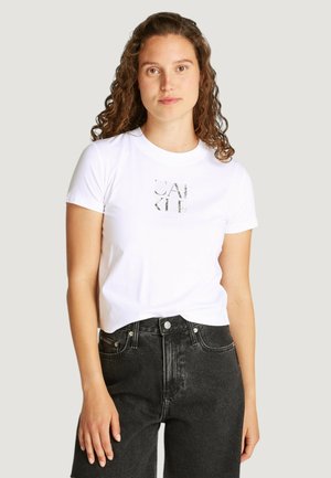 T-shirt bianco a maniche corte con stampa grafica sul frontale, abbinato a pantaloni corti neri in denim a vita alta. Tessuto morbido e vestibilità classica.