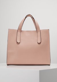 Růžová taška přes rameno z umělé kůže s dvěma horními uchy, čtvercový tvar, hladký povrch a černé lemování podél švů. Minimalistický design.