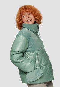 Gevoerde jas in lichtgroen met glanzende en ribbelstructuren, hoge kraag, ritsluiting, en een afneembare mini-tas die met een ketting is bevestigd.
