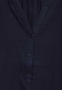 Camicia blu navy con bottoni, dotata di scollatura a V, realizzata in tessuto testurizzato, con patta con piccoli bottoni e vestibilità comoda.
