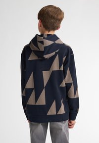 Sudadera azul marino con grandes patrones geométricos en color beige, con un bolsillo tipo canguro en la parte frontal y capucha con cordón, confeccionada en tejido suave.