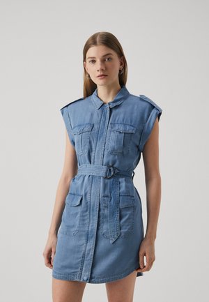 Robe en denim de couleur bleu clair, avec un col, des manches courtes, deux poches avant et une taille ceinturée. Texture lisse et design décontracté.
