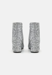 Silver glitter ankle boots with a block heel, smooth texture, and zip closure, featuring a shimmering finish on the exterior.
