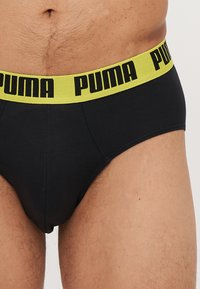 Fekete alsónadrág vastag, neon sárga derékpánttal, fekete "PUMA" logóval. Az anyag lágy és rugalmas.
