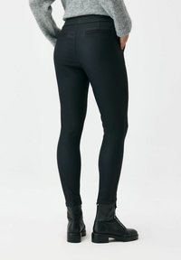 Czarne legginsy o gładkiej fakturze i dopasowanym kroju. Wyposażone w wysoki pas, kieszenie i zestawione z czarnymi botkami do kostki.
