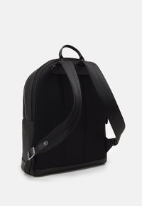 Μαύρο σακίδιο πλάτης με υφή, καμπυλωτό σχήμα, διπλούς ιμάντες ώμου και χειρολαβή στην κορυφή; διαθέτει πλαϊνό φερμουάρ και ελάχιστη σήμανση.