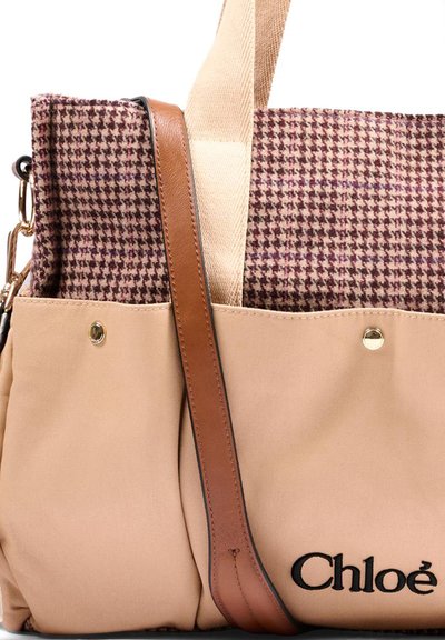 Borsa tote pied-de-poule beige e marrone con tracolla in pelle, tasche anteriori, borchie color oro e logo nero "Chloé" nell'angolo in basso a destra.