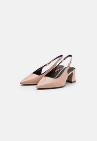 Slingback kengät, joissa on kapea varvas, kiiltävää nude-patenttia mustalla sisäpinnalla ja paksu korko. Varressa on kultasävyinen koriste.
