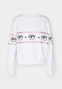 Vit sweatshirt med rund halsringning, med en horisontell design av ögon och ögonfransar i svart och blått, accentuerad med rosa och silverränder.