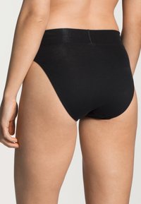 Zwarte katoenen slip met een gladde tailleband en hoge beenopeningen, met een eenvoudig ontwerp en zonder zichtbare patronen of hardware.