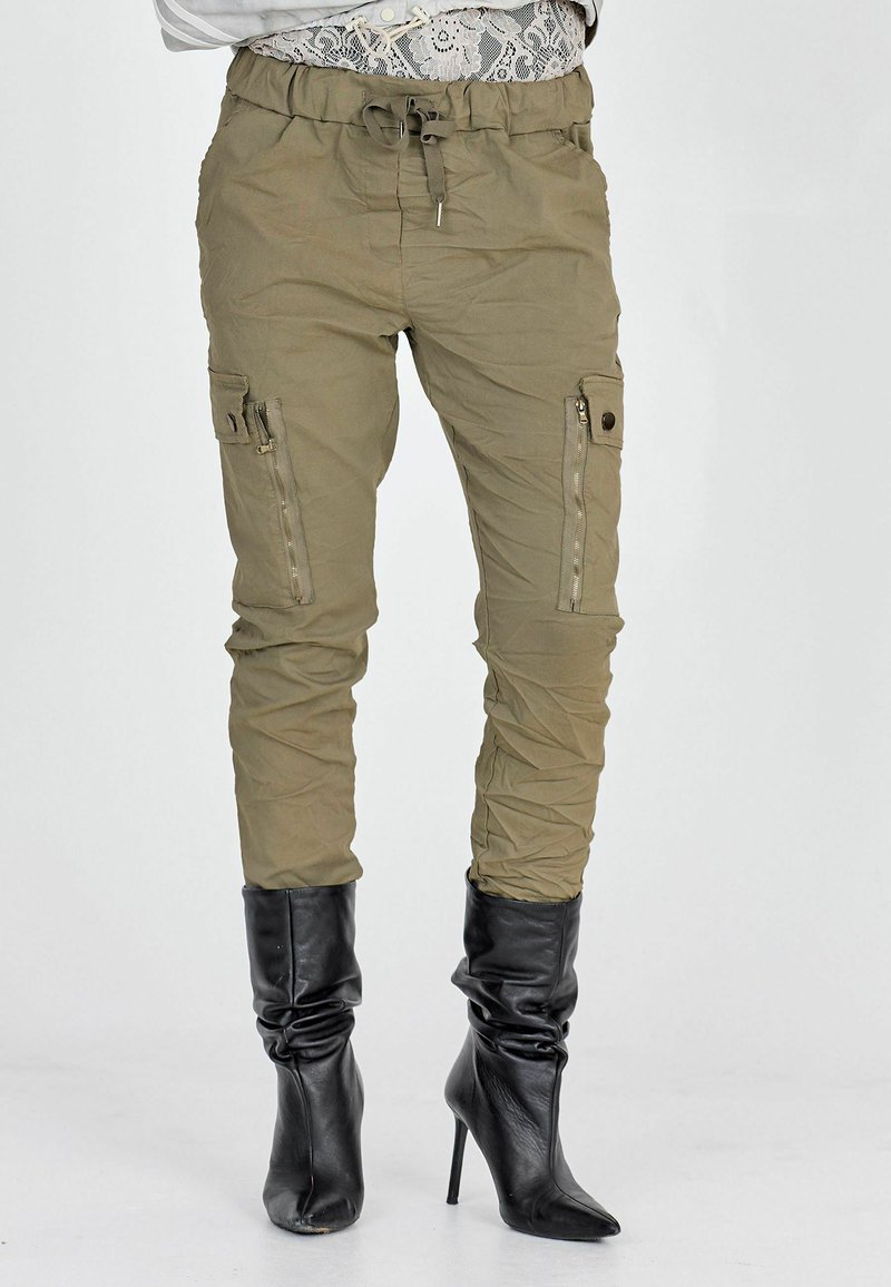 Pantaloni cargo verde oliva con cintura elastica, coulisse, zip laterali e due tasche cargo, abbinati a stivali neri con tacco alto.