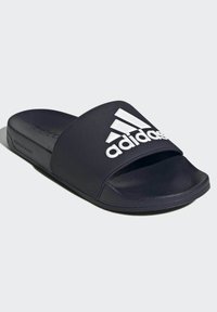 Tongs bleu marine en caoutchouc texturé avec une large sangle arborant un logo Adidas blanc. Design simple avec un bout ouvert.