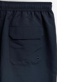 Șorturi bleu marin cu un brâu elastic, având un buzunar pătrat pe spate, accente cusute și un detaliu cu inel metalic.