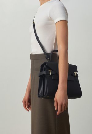 Black textured handbag with a structured design, gold-tone hardware, and a detachable shoulder strap. Worn against a neutral background.