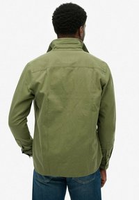 Grüne Baumwolljacke mit strukturiertem Kragen, langen Ärmeln und knöpfbaren Manschetten. Hat eine glatte Textur und ein lässiges Design.