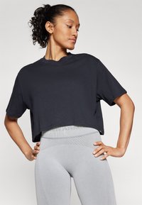 Black cropped t-shirt with short sleeves, round neckline, and smooth fabric. Paired with light gray, textured leggings featuring a ribbed waistband.