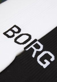 Schwarz-weiße gerippte Socken mit dem Wort "BORG", das in kontrastierenden Farben hervorgehoben ist. Material aus Baumwollmischung, Mittelschafthöhe.