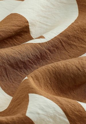 Linen fabric featuring an abstract design with large brown and white shapes, displaying a soft, textured surface and natural drape.