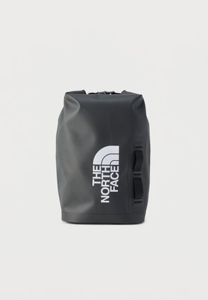 Μαύρο αδιάβροχο σακίδιο πλάτης με ρολό στην κορυφή, δύο πλαϊνά λουριά και μεγάλο λευκό λογότυπο "The North Face" μπροστά.