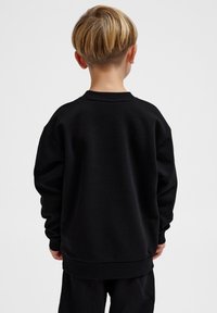 Svart långärmad sweatshirt med rund halsringning och ribbade mudd. Lös passform med en mjuk textur, med en enkel design utan mönster.