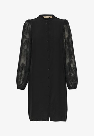 Fekete ruha mandarin gallérral és gombos záródással. Hosszú, áttetsző ujjak virágmintás hímzéssel díszítettek. Simább anyagú, laza fazonú.