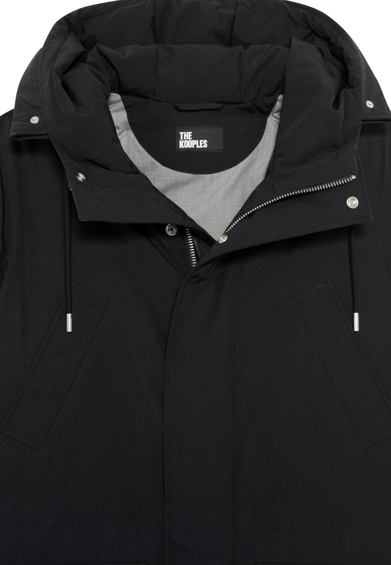 Black outerwear jacket featuring a padded hood, silver zipper, and textured front pockets with diagonal stitching details. Lined interior.