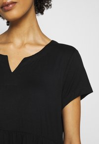 Robe noire à encolure en V avec manches courtes et texture froncée à la taille. Tissu doux et léger avec une finition lisse.